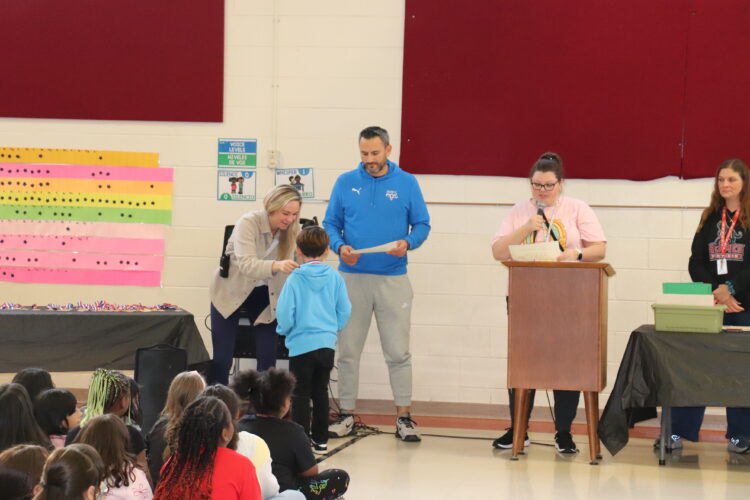 Mrs. Hawke and Mr. Contreras congratulate a 3rd grade student on his Honor Roll achievement.