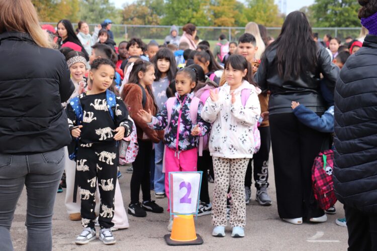 Students gather on the blacktop to dance the Cha-Cha Slide before walking into school together.