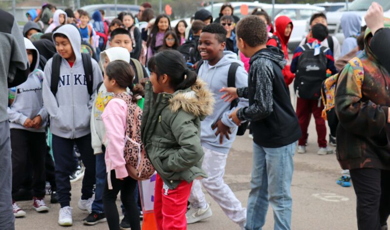 Students dance to the "Cha Cha Slide" on the blacktop before parading into the building.